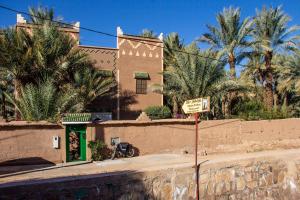 ein Straßenschild vor einem Gebäude mit Palmen in der Unterkunft Dar Nekhla in Zagora