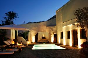 a house with a swimming pool in front of a building at Santorini Heritage Villas in Megalochori