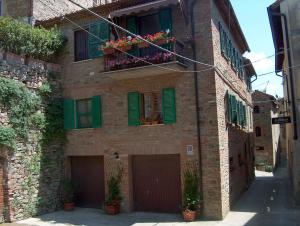 um edifício de tijolos com persianas verdes e flores nas janelas em Trasimeno Panicale - Appartamento borgo storico em Panicale