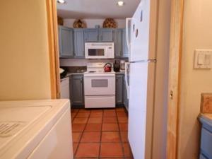 a kitchen with blue cabinets and a white refrigerator at Casas de Guadalupe - Sante Fe Vacation Rentals in Santa Fe