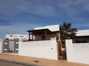 ein weißes Haus mit einem weißen Zaun und einer Palme in der Unterkunft apartamento el molino con piscina privada in Las Negras