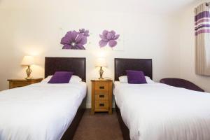 Duas camas num quarto com almofadas roxas em The New Inn Hotel em Stratford-upon-Avon