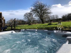 a hot tub with two glasses of wine at Deer lodge at Chapel Lodges in Wimborne Minster