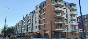 wysoki, czerwony, ceglany budynek na miejskiej ulicy w obiekcie Central Apartments Ogrody 1 & Parking w Gdańsku