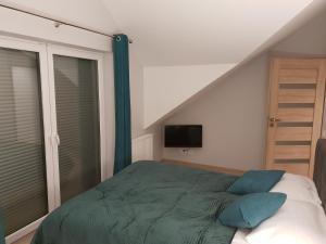 sypialnia z łóżkiem z zieloną pościelą i telewizorem w obiekcie Vera Apartment Świeradów-Zdrój Zakopiańska 22 C m10 w Świeradowie Zdroju