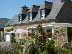 a stone house with flowers in front of it at La Kerandière in Tonquédec