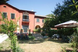una casa con una mesa y una sombrilla en el patio en Vigna dell'Agrifoglio - Bed and Breakfast, en Velletri