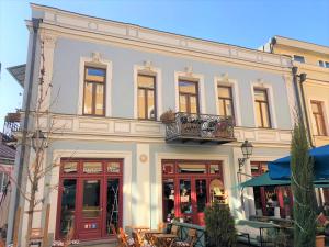Un gran edificio blanco con balcón y mesas. en Cibola Boutique - C, en Tiflis