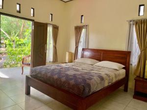 a bedroom with a bed and a large window at Tregge Surf Camp Uluwatu in Uluwatu