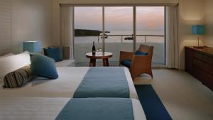 a hotel room with a bed and a view of the ocean at ANA InterContinental Manza Beach Resort by IHG in Onna