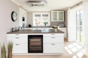 cocina con armarios blancos y encimera con horno en Beachalm en List