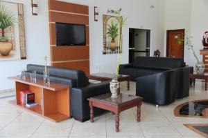 a living room with two black leather couches and a table at Vale do Sol Pousada Hotel in São José do Rio Pardo