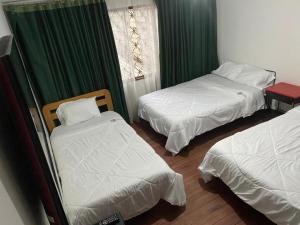 two beds in a room with green curtains at Hotel Don Olivo in Bogotá