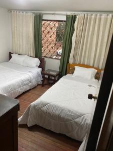 two beds in a room with a window at Hotel Don Olivo in Bogotá