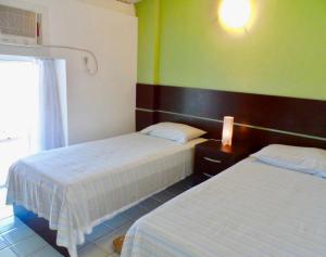 a hotel room with two beds and a window at Excelente Loft Ancorar in Porto De Galinhas +26 photos