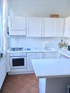 a white kitchen with white cabinets and a stove at Appartamento Ellen in Nago-Torbole