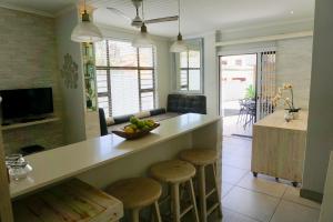 a kitchen with a counter with stools and a bowl of fruit at 10 Coral Cove in Ballito