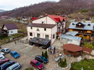 ein großes weißes Haus mit Autos auf einem Parkplatz in der Unterkunft Pensiunea Grande Lepsa in Lepşa