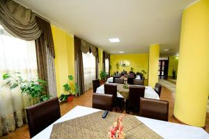 ein Restaurant mit Tischen und Stühlen und gelben Wänden in der Unterkunft Pensiunea Grande Lepsa in Lepşa