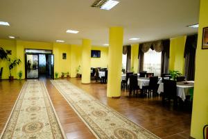 ein Esszimmer mit Tischen und Stühlen und gelben Wänden in der Unterkunft Pensiunea Grande Lepsa in Lepşa