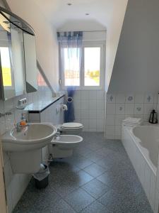 ein Badezimmer mit zwei Waschbecken, einem WC und einer Badewanne in der Unterkunft Ferienwohnung Elena in Oberstaufen