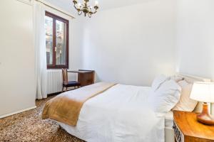 a white bedroom with a bed and a table and a chair at Del Remer Apartment - 5mins from San Marco sq in Venice