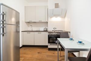 a kitchen with white cabinets and a table and a refrigerator at Del Remer Apartment - 5mins from San Marco sq in Venice
