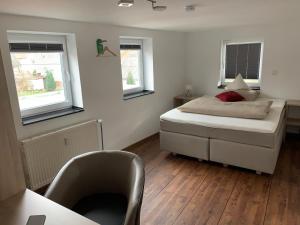 a small bedroom with a bed and two windows at Hotel Stegmann's Hof in Sehnde