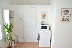 a white kitchen with a microwave on top of a refrigerator at Awesome Studio in Marolles in Brussels