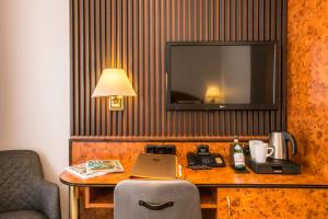 a hotel room with a desk with a laptop and a television at BARDOLINO Fine.Food.Hotel in Nuremberg