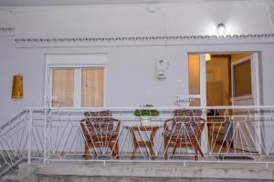 grupa krzeseł siedzących przy stole na balkonie w obiekcie Stefanie's Rooms 2 w mieście Asprovalta