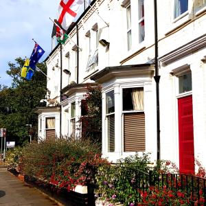 a white house with a red door and flags on it at Greenbank Hotel in Darlington