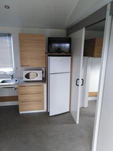 a kitchen with a white refrigerator and a microwave at Camping de Marcilly sur Vienne in Marcilly-sur-Vienne