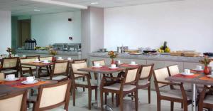 um restaurante com mesas e cadeiras de madeira e uma cozinha em Atmosfera Hotel em Feira de Santana