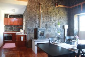 a kitchen with a table and a stone wall at Moinho da Cascata in Faja Grande