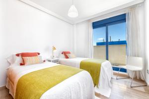 two beds in a white room with a window at iloftmalaga Ático Pacífico 19 B in Málaga