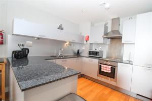 a kitchen with white cabinets and a black counter top at Dreamhouse Apartments Glasgow City Centre in Glasgow