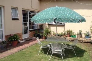 una mesa y sillas bajo una sombrilla en un patio en Clarens Socialites Garden Apartment #2, en Bethlehem