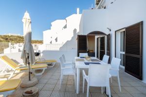 a patio with white chairs and a table and chairs at Top renoviertes Apartment mit großer Terrasse in Albufeira