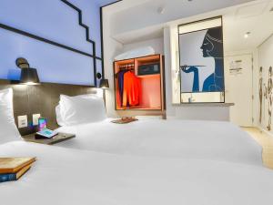 Cette chambre comprend un grand lit blanc et une fenêtre. dans l'établissement ibis Styles Goiania Marista, à Goiânia