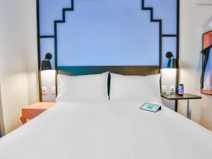 ibis Styles Goiania Marista في غويانيا: غرفة نوم بسرير ابيض كبير ومصباحين