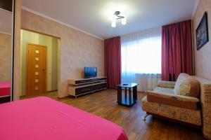 a bedroom with a bed and a chair and a television at ОК! Советская, 60 №1 in Tomsk