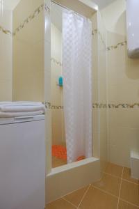 a shower with a white shower curtain in a bathroom at ОК! Советская, 60 №1 in Tomsk