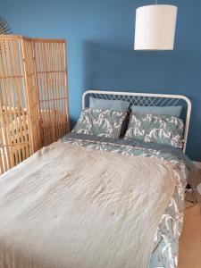 una cama en una habitación con una pared azul en Face mer Tyra, en La Baule