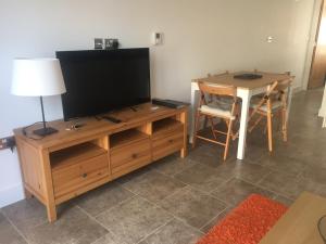 a television on a wooden entertainment center with a table at Cloverlea Cottages in Bristol