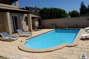 a swimming pool with two chairs next to a house at jolie villa avec piscine in Marignane
