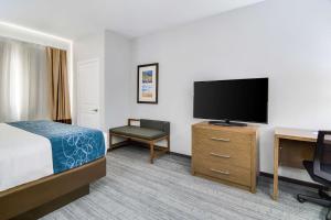a hotel room with a bed and a flat screen tv at Comfort Suites DeSoto Dallas South in DeSoto