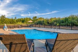 a swimming pool with two chairs and a fence at Comfort Suites DeSoto Dallas South in DeSoto