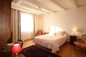 um quarto com uma cama branca e uma grande janela em Le Clos Marie em Brénod