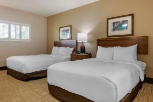 2 bedden in een hotelkamer met witte lakens bij Seafarer Inn & Suites, Ascend Hotel Collection in Jekyll Island